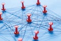 Network with red pins and string, An arrangement of colorful pins linked together with string on a blue background suggesting a Royalty Free Stock Photo