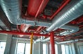 Network of red pipes and silver ducts installed in building ceiling. Firefighting sprinklers system infrastructure, MPE systems, Royalty Free Stock Photo