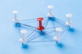 Network with red and white pins and string, An arrangement of colorful pins linked together with string on a blue background Royalty Free Stock Photo