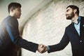 The networking pros. two young businessmen shaking hands in a modern office. Royalty Free Stock Photo