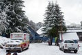 View of vehicles, people and pine trees at the foot of Cerro Bayo Bayo Hill on a spring cloudy and snowy day in Villa La Angostu