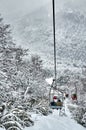 Wide vertical view going down on the cable car at Cerro Bayo, with tourists enjoying the view full of snow, white forests and moun