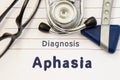 Neurological diagnosis of Aphasia. Neurological hammer, stethoscope and doctor`s glasses lie on doctor workplace on sheet of noteb Royalty Free Stock Photo