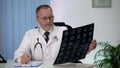 Neurologist carefully studying brain MRI, disturbed by results, making notes