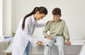 Neurologist examining a happy little boy and using a hammer to test his knee reflex Royalty Free Stock Photo