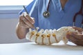 A neurosurgeon pointing at lumbar vertebra model in medical off