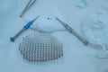 Neurosurgical instruments, including a titanium plate for implantation in the skull, are on the sterile operating table of a nurse