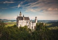 Neuschwanstein Castle on a rugged hill against a backdrop of picturesque mountain scenery in Bavaria