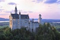 Neuschwanstein Castle viewed from Marienbrucke at dusk with purple sky on the background