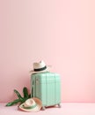Neutral green suitcase and two straw hats. Stylish luggage bag on pink background with blank space for text. Travel and vacation