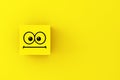 Neutral or surprised emoticon face on a yellow cube block Royalty Free Stock Photo