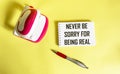 Never be sorry for being real. Inspirational phrases on a notepad, next to a stapler and a pen on a yellow background.