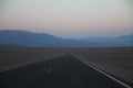 The never ending road during the dusk of a sunset in the Death Valley desert