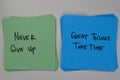 Never Give Up - Great Things Take Time write on sticky notes isolated on Wooden Table
