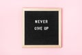 Never give up. Motivational quote on black letter board on pink background. Concept inspirational quote of the day. Greeting card Royalty Free Stock Photo