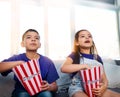 Never miss a scene of the action. two young children sitting on a sofa and eating popcorn while watching movies at home. Royalty Free Stock Photo