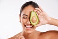 She never neglects her skin. Studio shot of a beautiful young woman holding half an avocado against a gray background. Royalty Free Stock Photo