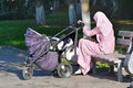 Nevinnomyssk, Russia, September, 13, 2018. Muslim woman sitting on a bench and cradles a child in a wheelchair on the Boulevard of