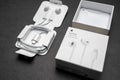 New Apple Earpods, Airpods white earphones for listening to music and podcasts in an open box. Isolated black background. Budapest