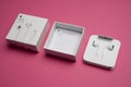 New Apple Earpods, Airpods white earphones for listening to music and podcasts in an open box. Isolated pink background. Budapest