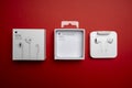 New Apple Earpods, Airpods white earphones for listening to music and podcasts in an open box. Isolated red background.