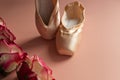new ballet slippers lying on pink background with roses. elegant ballet shoes with bouquet Royalty Free Stock Photo
