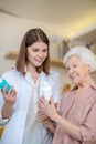 Young dark-haired cosmetologist demonstrating new cosmetic products to a female customer Royalty Free Stock Photo