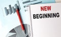 NEW BEGINNING text on a notebook with pen on a chart background Royalty Free Stock Photo