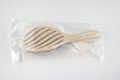 New beige oval hairbrush with bristles and a white tag in a transparent plastic package