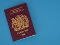 New Bergundy UK passport, no longer showing words `European Union`. On blue surface.