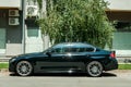 New black custom BMW 5 series with alloy wheels parked on the street.