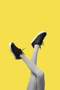 New Black female sneakers on long slender woman legs in gray tights isolated on yellow background Royalty Free Stock Photo