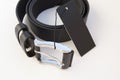 New black leather men`s belt on a white background with a black label Royalty Free Stock Photo
