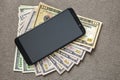 New black modern cellphone on money dollars banknotes background. Modern technology, communication and online trade using gadget