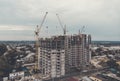 A new block of flats is erected in a low-rize houses town area. Process of housing. Town housing development problems. Large-sized