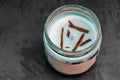 New blue candle with brown twigs and marine scent in a glass jar on a slate plate. Aromatic candle