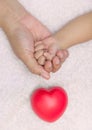 New born baby hand in mom palm with red heart Royalty Free Stock Photo