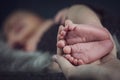 New born baby`s feet in mother hands, sleeping baby in the background