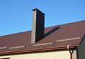 New brown metal tiled roof with plastic rain gutter system and chimney