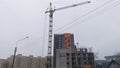 The new building is being built among the residential buildings of the city block with the help of a crane. Nearby there is a powe Royalty Free Stock Photo