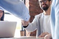 New business partners. Young modern colleagues in smart casual wear shaking hands and smiling while sitting in the Royalty Free Stock Photo