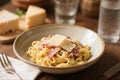Italian pasta carbonara served in ceramic bowl with parmesan cheese on top, cozy dining setting Royalty Free Stock Photo