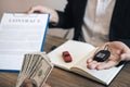 New car buyers are holding cash and handing it to car salespeople while filing a new car signing contract for car buyers Royalty Free Stock Photo