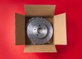 New car parts. Box with a new ventilated brake discs on a red background.