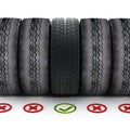 New car tire with green check mark standing out among old tires Royalty Free Stock Photo