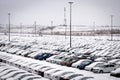 New cars covered with snow and parked in a distribution center on a cloudy day in the winter, a car factory