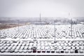 New cars covered with snow and parked in a distribution center on a cloudy day in the winter, a car factory