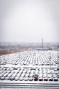 New cars covered with snow and parked in a distribution center on a cloudy day in the winter, a car factory