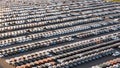 New cars stand in even rows in a gigantic parking lot.