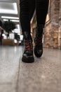 New collection of winter stylish women`s boots. Closeup of fashionable leather black shoes with red shoelaces on female legs.